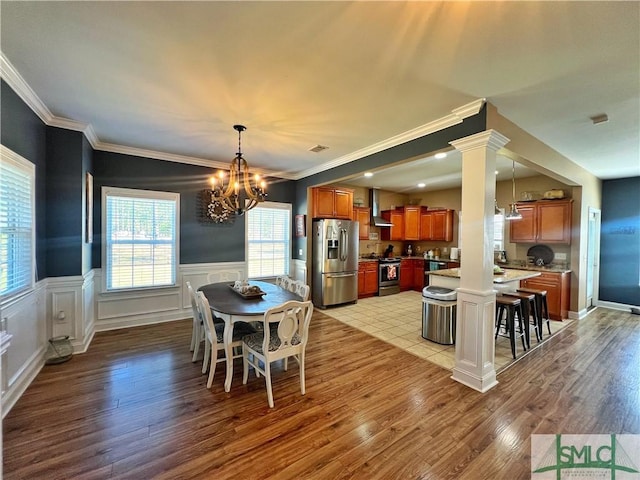 98 Vickers Rd SE, Ludowici, GA 31316 - dining area with ornamental molding, light wood finished floors, a chandelier, wainscoting, and decorative columns