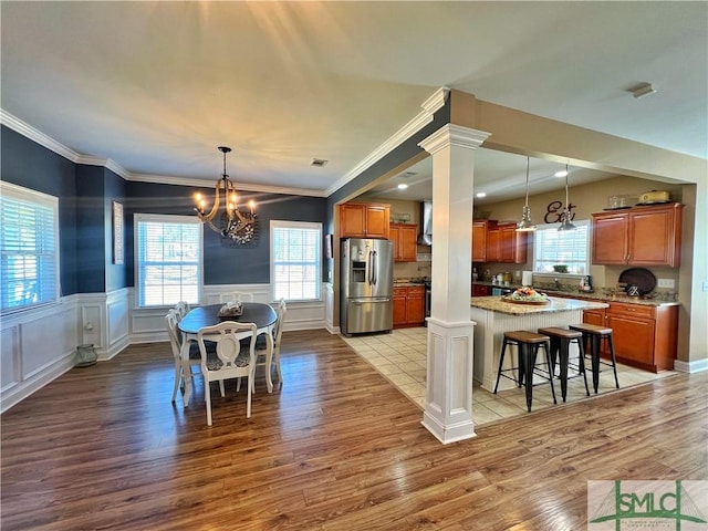 98 Vickers Rd SE, Ludowici, GA 31316 - kitchen with stainless steel refrigerator with ice dispenser, brown cabinetry, ornate columns, light wood-style flooring, and a wainscoted wall