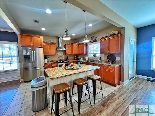 98 Vickers Rd SE, Ludowici, GA 31316 - kitchen featuring stainless steel appliances, wall chimney range hood, a sink, light wood-style floors, and a kitchen breakfast bar
