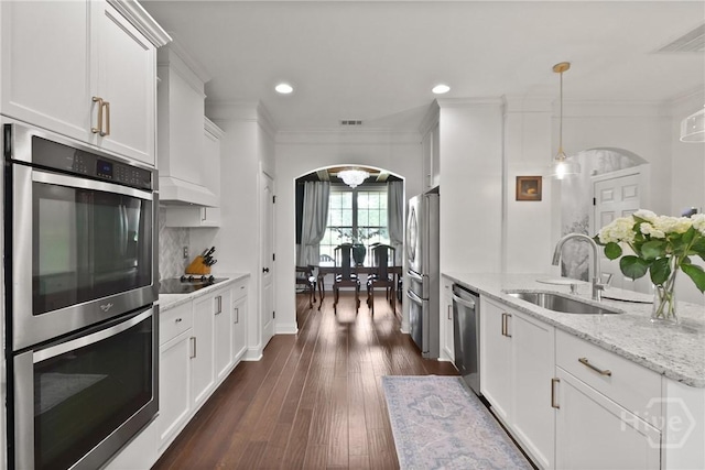 447 Walthour Dr, Rincon, GA 31326 - kitchen with appliances with stainless steel finishes, a sink, arched walkways, white cabinetry, and ornamental molding