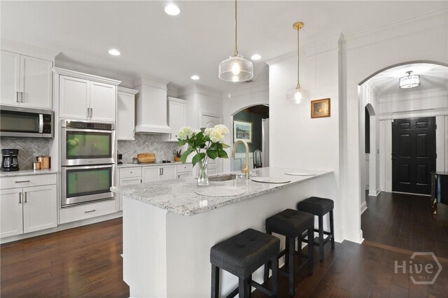 447 Walthour Dr, Rincon, GA 31326 - kitchen featuring appliances with stainless steel finishes, arched walkways, a sink, a breakfast bar area, and recessed lighting