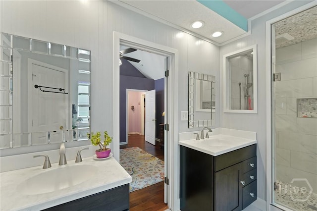 bathroom featuring a shower stall, two vanities, wood finished floors, a ceiling fan, and recessed lighting