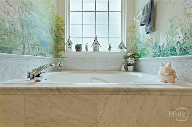 bathroom with wallpapered walls, a bath, and wainscoting