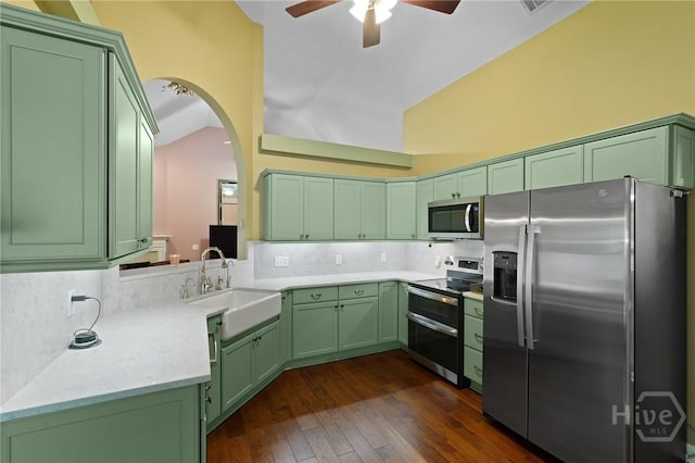 kitchen with appliances with stainless steel finishes, green cabinets, a sink, a ceiling fan, and decorative backsplash