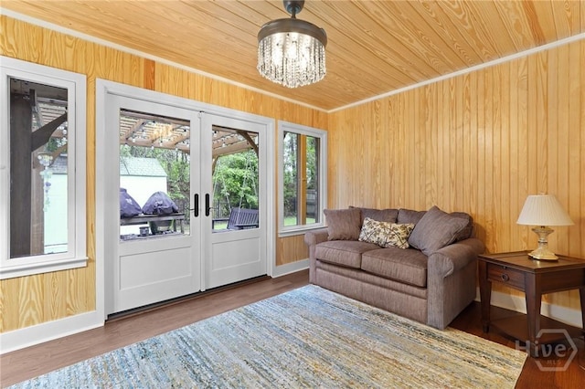 living area with french doors, wooden walls, a chandelier, baseboards, and wooden ceiling