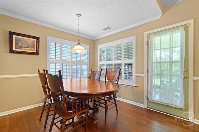 dining space with a textured ceiling, crown molding, wood finished floors, and baseboards
