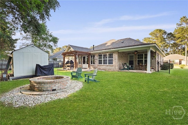back of house featuring an outdoor fire pit, a patio area, brick siding, a pergola, and an outdoor structure