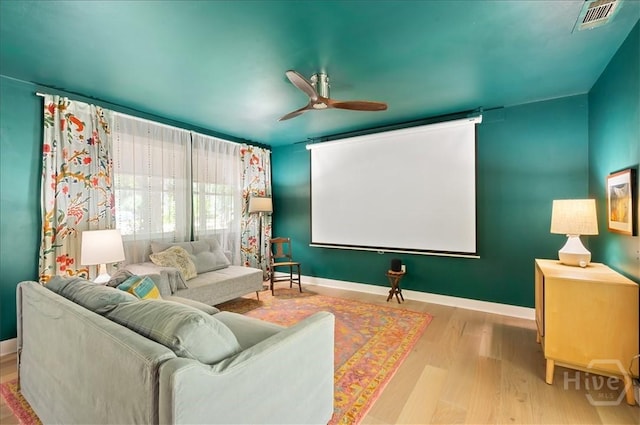 cinema with wood finished floors, ceiling fan, and baseboards