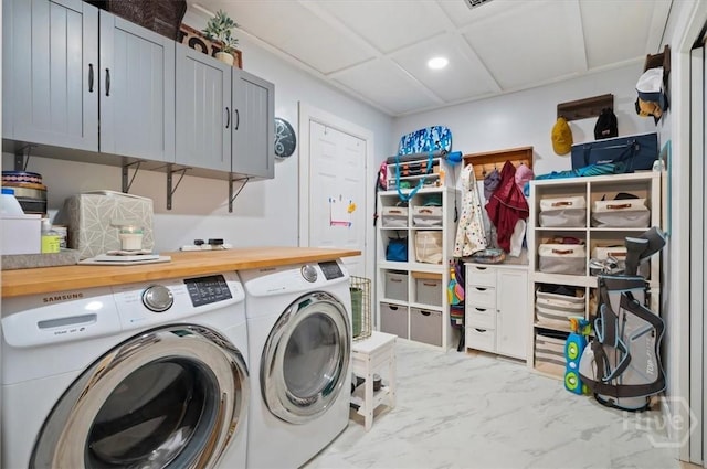 clothes washing area with washing machine and dryer, marble look tiles, cabinet space, and recessed lighting