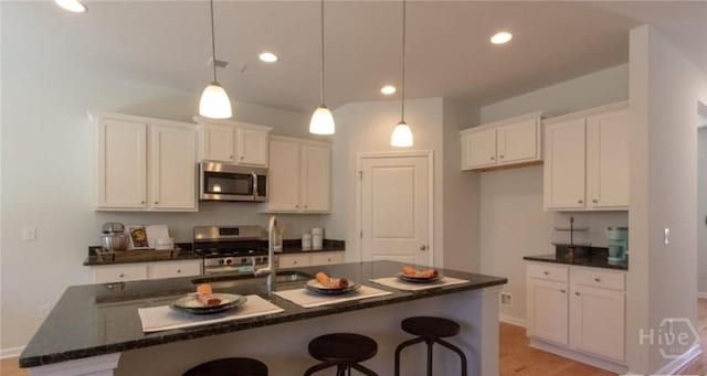 119 Fremont Ln, Pooler, GA 31322 - kitchen featuring appliances with stainless steel finishes, a breakfast bar, white cabinetry, a sink, and light wood-style floors
