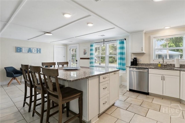 1212 2nd Ave, Tybee Island, GA 31328 - kitchen featuring stainless steel dishwasher, a sink, light tile patterned flooring, a breakfast bar, and light stone countertops