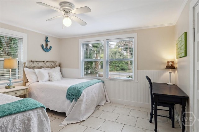 1212 2nd Ave, Tybee Island, GA 31328 - bedroom featuring multiple windows, a wainscoted wall, light tile patterned floors, a ceiling fan, and baseboards
