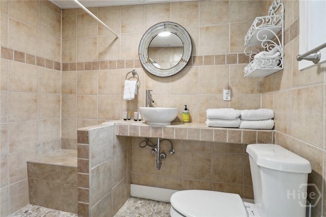 1212 2nd Ave, Tybee Island, GA 31328 - full bathroom with a sink, toilet, tiled shower, and tile walls