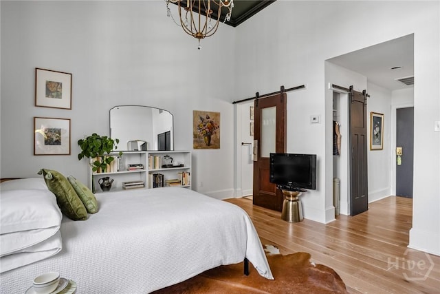 321 Abercorn St Unit 404, Savannah, GA 31401 - bedroom featuring a barn door, wood finished floors, baseboards, a high ceiling, and a chandelier