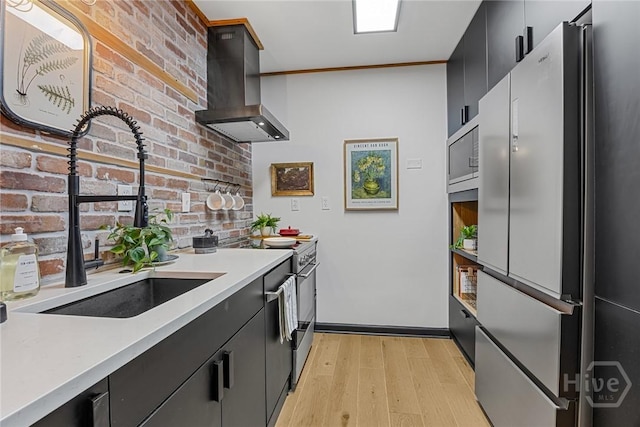 321 Abercorn St Unit 404, Savannah, GA 31401 - kitchen with appliances with stainless steel finishes, wall chimney exhaust hood, dark cabinetry, a sink, and light wood finished floors