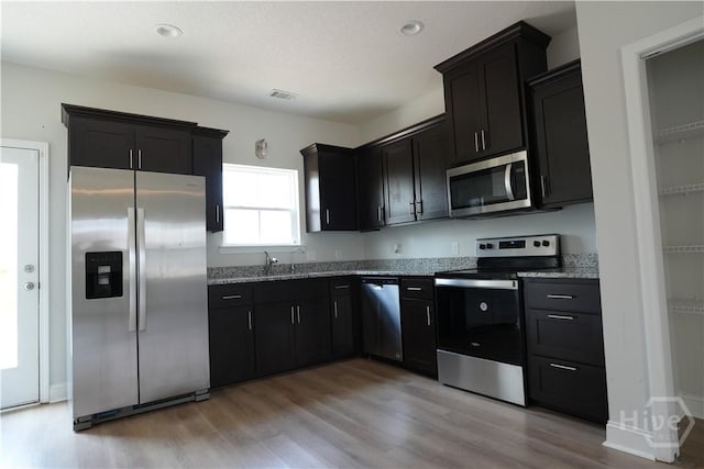 141 Mcclelland Loop NE, Ludowici, GA 31316 - kitchen with stainless steel appliances, light stone countertops, light wood-style flooring, and dark cabinetry