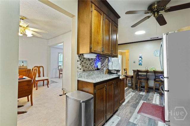3010 Leonard St, Savannah, GA 31404 - kitchen with freestanding refrigerator, a ceiling fan, tasteful backsplash, and light stone counters