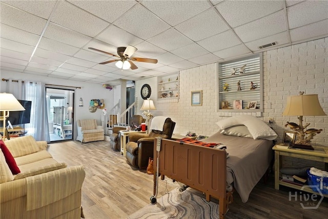3010 Leonard St, Savannah, GA 31404 - living room with wood finished floors, a drop ceiling, a ceiling fan, and brick wall