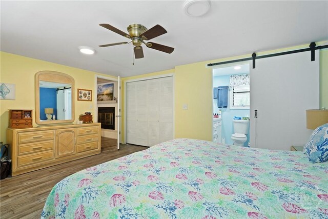 3010 Leonard St, Savannah, GA 31404 - bedroom with wood finished floors, ensuite bath, a barn door, a closet, and a ceiling fan