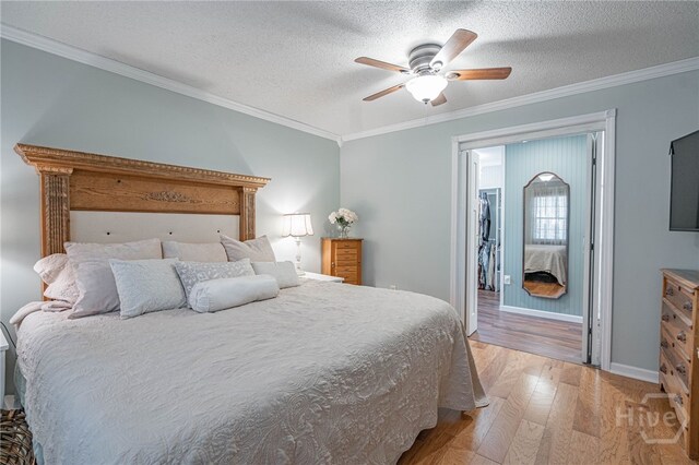 116 Deerfield Dr, Springfield, GA 31329 - bedroom with light wood-style flooring, crown molding, a walk in closet, a ceiling fan, and a textured ceiling