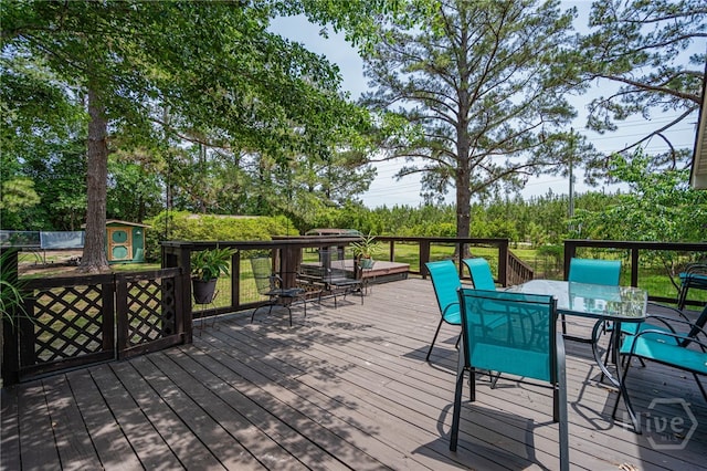 116 Deerfield Dr, Springfield, GA 31329 - wooden deck featuring outdoor dining area, a storage unit, an outbuilding, and view of scattered trees
