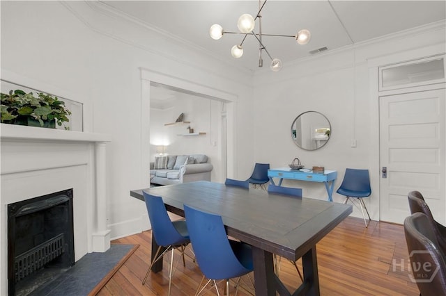 117 Lincoln St Unit 4A, Savannah, GA 31401 - dining area featuring ornamental molding, a chandelier, wood finished floors, a fireplace, and baseboards