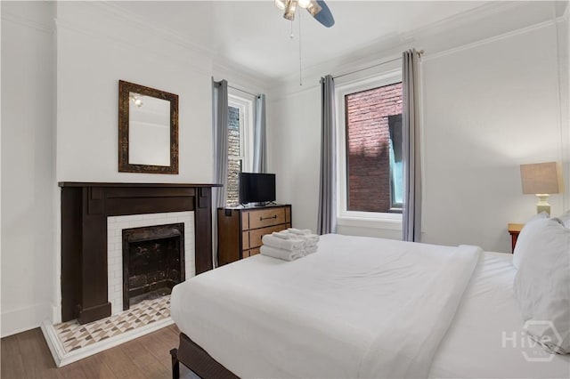 117 Lincoln St Unit 4A, Savannah, GA 31401 - bedroom featuring wood finished floors, ornamental molding, a fireplace, ceiling fan, and baseboards