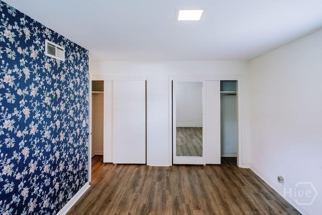 1 Broadmoor Cir, Savannah, GA 31406 - unfurnished bedroom featuring two closets, wallpapered walls, wood finished floors, and baseboards