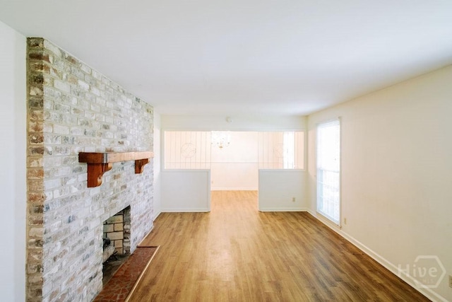 1 Broadmoor Cir, Savannah, GA 31406 - unfurnished living room featuring wood finished floors, a brick fireplace, and baseboards