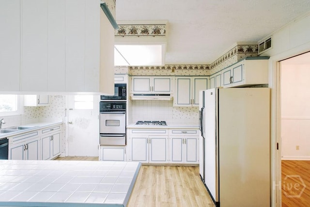 1 Broadmoor Cir, Savannah, GA 31406 - kitchen featuring stainless steel appliances, a warming drawer, tile counters, under cabinet range hood, and a sink
