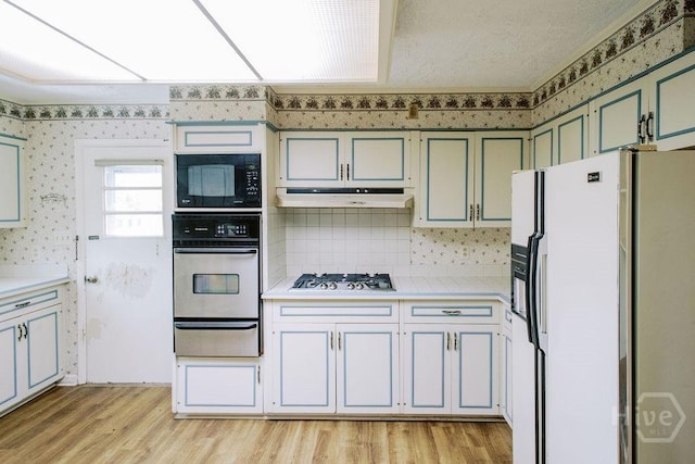 1 Broadmoor Cir, Savannah, GA 31406 - kitchen with stainless steel appliances, a warming drawer, light countertops, wallpapered walls, and light wood-type flooring