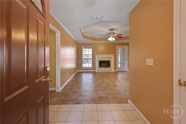 1919 Bluestone Loop, Hinesville, GA 31313 - unfurnished living room featuring ceiling fan, a tray ceiling, baseboards, ornamental molding, and a tiled fireplace