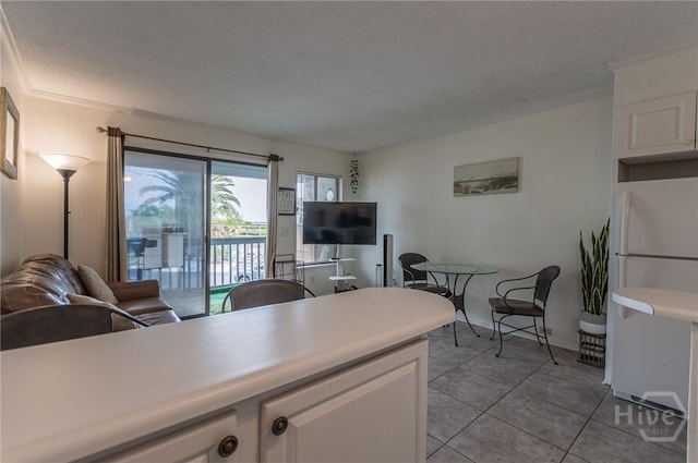 1217 Bay St Unit 107B, Tybee Island, GA 31328 - kitchen featuring freestanding refrigerator, white cabinetry, light tile patterned flooring, a textured ceiling, and light countertops