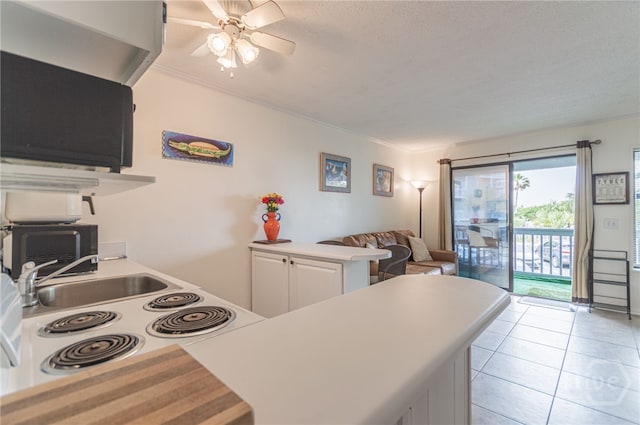 1217 Bay St Unit 107B, Tybee Island, GA 31328 - kitchen featuring ceiling fan, light countertops, a peninsula, white cabinetry, and a sink