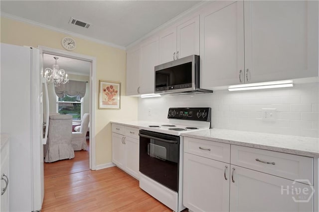 1 Black Forest Dr, Savannah, GA 31410 - kitchen with range with electric stovetop, stainless steel microwave, freestanding refrigerator, ornamental molding, and white cabinets