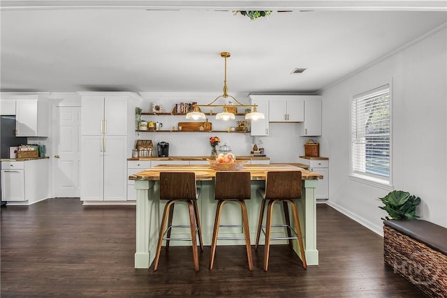 737 Te Glisson Rd, Ellabell, GA 31308 - kitchen with wooden counters, dark wood-style floors, white cabinetry, a breakfast bar area, and ornamental molding