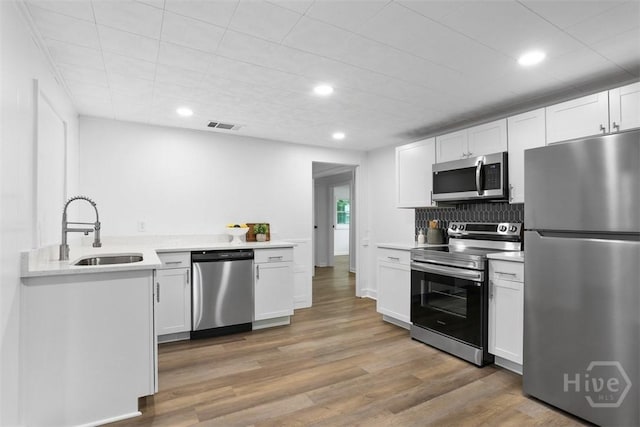 72 Bazemore Ave, Savannah, GA 31408 - kitchen featuring stainless steel appliances, a sink, white cabinets, light wood finished floors, and light countertops