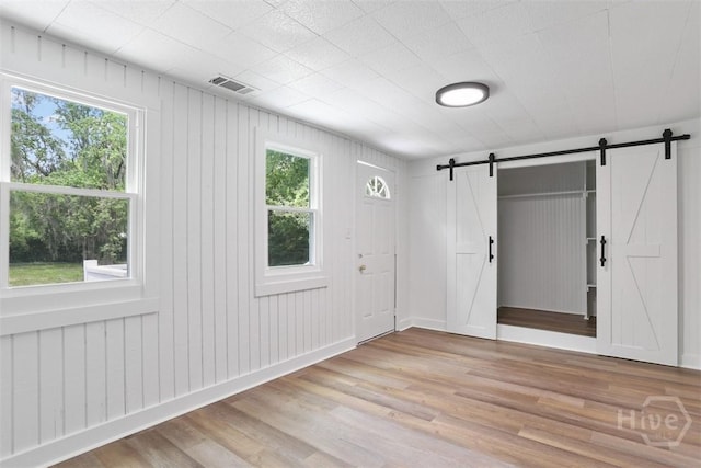 72 Bazemore Ave, Savannah, GA 31408 - unfurnished room with a barn door, healthy amount of natural light, and light wood finished floors