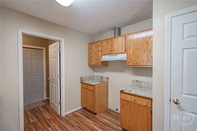 145 New Stillwell Rd, Springfield, GA 31329 - kitchen featuring under cabinet range hood, dark wood-style floors, light countertops, a textured ceiling, and brown cabinetry