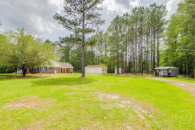1282 Long Bridge Rd, Rincon, GA 31326 - view of grassy yard featuring a garage, an outdoor structure, and view of wooded area