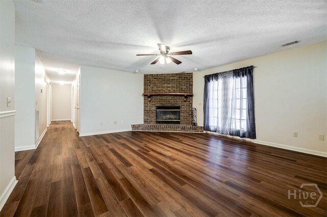 1282 Long Bridge Rd, Rincon, GA 31326 - unfurnished living room with a ceiling fan, dark wood-type flooring, a textured ceiling, baseboards, and a brick fireplace