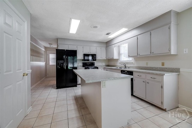 1282 Long Bridge Rd, Rincon, GA 31326 - kitchen featuring black appliances, light countertops, light tile patterned floors, a center island, and a textured ceiling