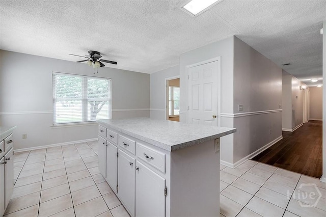 1282 Long Bridge Rd, Rincon, GA 31326 - kitchen featuring light tile patterned floors, a textured ceiling, a ceiling fan, a center island, and white cabinetry