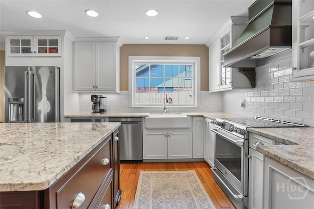 6 Cutty Sark Rd, Savannah, GA 31410 - kitchen with appliances with stainless steel finishes, premium range hood, a sink, light wood-style floors, and light stone counters