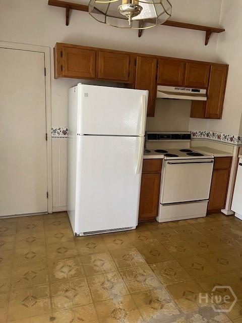 887 Piercefield Dr, Richmond Hill, GA 31324 - kitchen featuring white appliances, under cabinet range hood, and brown cabinetry