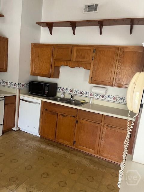 887 Piercefield Dr, Richmond Hill, GA 31324 - kitchen with black microwave, dishwasher, a sink, brown cabinetry, and light countertops