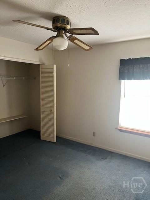 887 Piercefield Dr, Richmond Hill, GA 31324 - unfurnished bedroom with dark colored carpet, a closet, baseboards, a textured ceiling, and ceiling fan
