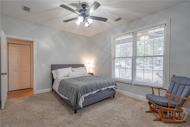 bedroom with carpet, a textured ceiling, baseboards, and a ceiling fan