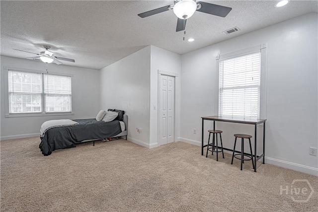 bedroom with carpet flooring, a textured ceiling, a closet, baseboards, and a ceiling fan