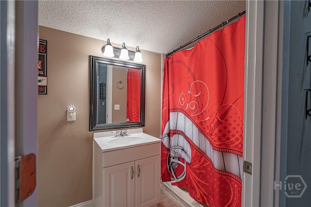 full bath featuring a textured ceiling, vanity, and baseboards